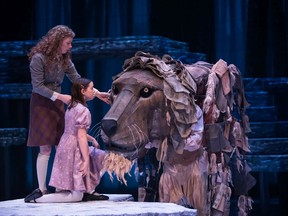 Siblings Susan (Anna Dalgleish), left, and Lucy (Annabel Beames) greet Aslan the lion (played by Bruce Horak and Jerod Blake) in ATP's The Lion, the Witch and the Wardrobe. Courtesy Benjamin Laird