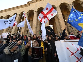 Georgian opposition supporters wave Georgian and European flags as they protest outside the parliament in central Tbilisi on November 17, 2019, to demand the government's resignation and early parliamentary polls. - In the biggest anti-government rally in years, protesters demonstrated outside the parliament building on the capital Tbilisi's main thoroughfare. AFP journalists estimated the crowd at more than 20,000. Demanding the government's resignation and snap parliamentary polls, the crowd waved Georgian and European Union flags, lit coloured flares and held up a giant banner with the anti-Ivanishvili slogan "All Against One". (Photo by Vano Shlamov / AFP) (Photo by VANO SHLAMOV/AFP via Getty Images)