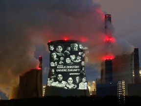 Activists of the environmental organization Greenpeace project a slogan that reads "No Future in Fossil Fuels" on the cooling tower of RWE coal power plant, one of Europe's biggest electricity companies in Neurath, north-west of Cologne, Germany, Nov. 10, 2017.