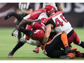 CP-Web.  B.C. Lions' Brandon Rutley, bottom, is tackled by Calgary Stampeders' Lorenzo Jerome, left, Nate Holley, right, and Sterling Sheffield, back, during first half CFL football action in Vancouver, Saturday, Nov. 2, 2019.