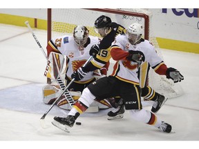 CP-Web.  Pittsburgh Penguins' Jared McCann (19) tries to get a shot off in from of Calgary Flames goaltender David Rittich (33) with TJ Brodie (7) defending during the first period of an NHL hockey game in Pittsburgh, Monday, Nov. 25, 2019.
