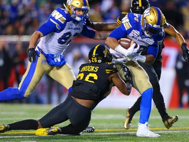 Andrew Harris of the Winnipeg Blue Bombers avoids a tackle from Hamilton Tiger-Cats Cariel Brooks during the 107th Grey Cup CFL championship football game in Calgary on Sunday, November 24, 2019. Al Charest/Postmedia