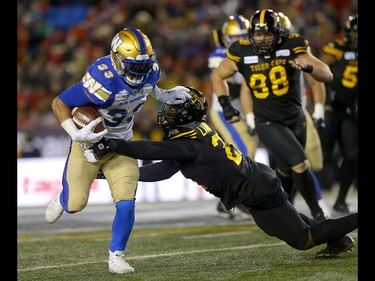 Winnipeg Blue Bombers, Andrew Harris  is taken down by the Hamilton Tiger-Cats, Simoni Lawrence at McMahon stadium during the 107th Grey Cup in Calgary on Sunday, November 24, 2019. Darren Makowichuk/Postmedia