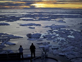 FILE - In this July 21, 2017 file photo, researchers look out from the Finnish icebreaker MSV Nordica as the sun sets over sea ice in the Victoria Strait along the Northwest Passage in the Canadian Arctic Archipelago. Studies show the Arctic is heating up twice as fast as the rest of the planet. Scientists are concerned because impacts of a warming Arctic may be felt elsewhere. (AP Photo/David Goldman, File) ORG XMIT: NY932