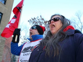 AUPE representative Stephen Michaud and support worker Kelly Michaud protest government cuts at a rally outside McDougall Centre on Friday, Nov. 29, 2019.