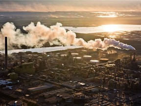 The setting sun reflects off a tailings pond behind Syncrude's oilsands upgrading facility north of Fort McMurray, Alta. on June 18, 2013.