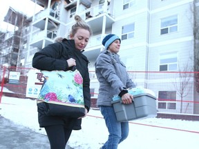 Megan Dugdale (L) walks with friend Joy Elder after the pair gathered some belongings from Dugdale's third floor condo on 14 St SW in Calgary on Saturday, December 28, 2019 Dugdale's condo was virtually destroyed when fire ripped through the fourth and fifth floor of the condo building last week. Jim Wells/Postmedia