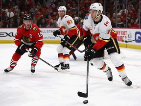 CHICAGO, ILLINOIS - JANUARY 07: Mark Jankowski #77 of the Calgary Flames looks to pass as Jonathan Toews #19 of the Chicago Blackhawks moves in at the United Center on January 07, 2020 in Chicago, Illinois. (Photo by Jonathan Daniel/Getty Images)