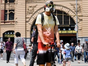 A commuter riding his scooter wears a mask as poor air quality from Australia's bushfires have hampered qualifying for the upcoming Australian Open tennis tournament in Melbourne on January 15, 2020. (Photo by William WEST / AFP) (Photo by WILLIAM WEST/AFP via Getty Images)