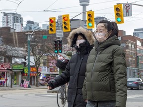 Pedestrians wear protective masks as they walk in Toronto on Monday, Jan. 27, 2020. Canada's first presumptive case of the novel coronavirus has been officially confirmed, Ontario health officials said Monday as they announced the patient's wife has also contracted the illness.