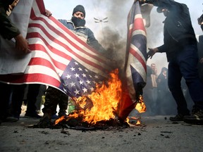 Demonstrators burn the U.S. and British flags during a protest against the assassination of the Iranian Major-General Qassem Soleimani, head of the elite Quds Force, and Iraqi militia commander Abu Mahdi al-Muhandis who were killed in an air strike in Baghdad airport, in Tehran, Iran January 3, 2020.