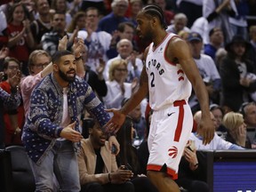 Toronto Raptors Kawhi Leonard SF (2) gets a low five from Drake as he exits the game during the second half in Toronto, Ont. on Saturday April 27, 2019.