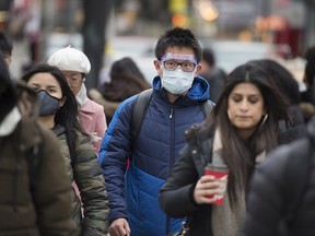 A pedestrian wears a mask and goggles while on Yonge Street in Toronto on Tuesday, Jan. 28, 2020.