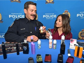 Const. Bryan Alm, Edmonton Police Service school resource officer for Victoria School of the Arts, and Brenna Grewal, a nursing student involved with the teen vaping educational campaign, look over vaping products seized from students in Edmonton, June 25, 2019. They are bringing attention to the growing issue of youth vaping and flavoured nicotine use in schools.