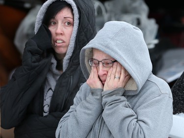 An upset Ursla Waldeck and her niece watch as Police and bylaw officers remove about 25 dogs from their neighbour’s home on Malvern Crescent N.E. on Thursday February 13, 2020. Waldeck had helped care for the animals over the past year.