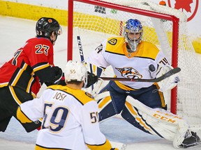 Nashville Predators goaltender Juuse Saros tracks the puck in front of Calgary Flames forward Sean Monahan in NHL action at the Scotiabank Saddledome in Calgary on Saturday December 8, 2018.