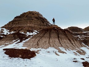 An image of a person standing on a hill in the Canadian Badlands near Drumheller, Alberta, Canada in winter.