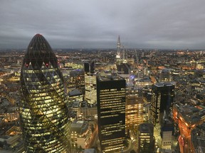 The Swiss Re Insurance building, also known as "the Gherkin", left, and St Helens, the Aviva Plc building, centre, stand illuminated in the city of London, U.K.
