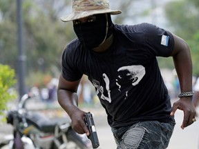 A protester carrying a gun runs during a shooting at a protest called by members of the police, in Port-au-Prince, Haiti February 23, 2020.