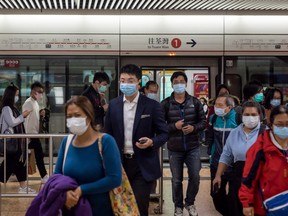 Passengers wearing protective masks disembark a train operated by MTR Corp. in Hong Kong, China, on Tuesday, Feb. 4, 2020.