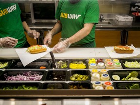 Employees work behind the counter at a Subway restaurant.
