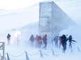 Journalists and cameramen walk under a gust of cold wind near the entrance of the Svalbard Global Seed Vault that was officially opened near Longyearbyen on February 26, 2008.