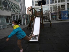 A child wearing a face mask plays near a slide at a commercial and residential complex in Beijing's central business district on Feb. 18, 2020.