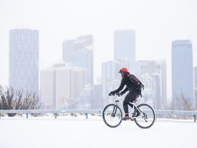 A cyclist rides on fresh snow in Crescent Heights as the Winter makes a comeback on Friday, March 13, 2020.