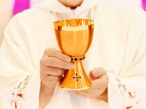 A priest holds communion cup in this undated file photo.