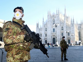 Military officers wearing face masks stand outside Duomo cathedral, closed by authorities due to a coronavirus outbreak, in Milan, Italy February 24, 2020.
