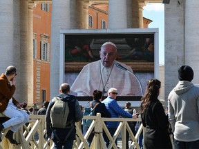 People watch a screen live-broadcasting Pope Francis' Sunday Angelus prayer on St. Peter's Square at the Vatican on March 8, 2020, after millions of people were placed under forced quarantine in northern Italy as the government approved drastic measures in an attempt to halt the spread of the COVID-19 outbreak, caused by the novel coronavirus that is sweeping the globe. - On top of the forced quarantine of 15 million people in vast areas of northern Italy until April 3, the government has also closed schools, nightclubs and casinos throughout the country, according to the text of the decree published on the government website. With more than 230 fatalities, Italy has recorded the most deaths from the COVID-19 disease of any country outside China, where the outbreak began in December. (Photo by Alberto PIZZOLI / AFP) (Photo by ALBERTO PIZZOLI/AFP via Getty Images)