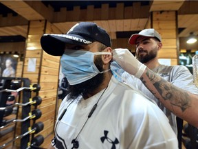 A bearded weightlifter gets a protective mask tied on as he starts training. (Photo by Haidar HAMDANI / AFP)