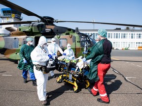 Medical staff transport a French patient infected with the new coronavirus in an intensive care bed after arriving in a helicopter from Metz, northeastern France, to a hospital in Essen, western Germany, on March 28, 2020.