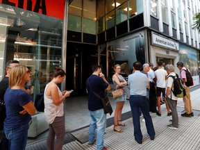 Travellers queue outside the American Airlines offices in Buenos Aires to change their flights due to the coronavirus outbreak on Friday, March 13, 2020.