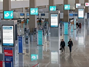 Travellers walk through a quiet international wing at the Calgary International Airport on Monday, March 16, 2020.