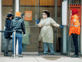 A nurse speaks to people asking for a COVID-19 test at St. Michael's Hospital in Toronto, March 30, 2020.