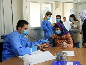 A doctor checks the blood pressure of a Yazidi displaced woman, as they wear protective face masks, following the coronavirus outbreak, at medical Center in the Sharya camp in Duhok, Iraq March 7, 2020. REUTERS/Ari Jalal ORG XMIT: GGGBAG540