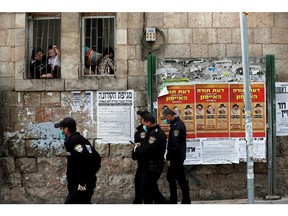 Israeli policemen wearing masks talk to residents from their window as they enforce government restrictions placed to curb the spread of the coronavirus disease (COVID-19) in Mea Shearim neighbourhood of Jerusalem March 26, 2020. REUTERS/Ronen Zvulun ORG XMIT: PPPJER03