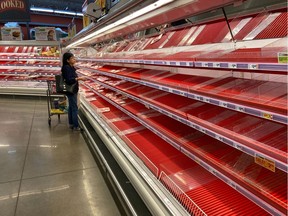 A shopper picks over the few items remaining in the meat section, as people stock up on supplies amid coronavirus fears, at an Austin, Texas, grocery store on March 13, 2020.