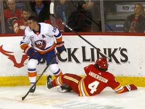 Calgary Flames Rasmus Andersson takes a hit from New York Islanders Cal Clutterbuck in third period action at the Scotiabank Saddledome in Calgary on Wednesday February 20, 2019. Darren Makowichuk/Postmedia