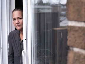 Melanie Fournier, who has contracted the COVID-19 virus, peers out the patio door of her home in Montreal on Thursday, March 26, 2020.