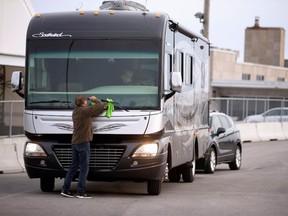 A man cleans the window of his recreational vehicle after crossing the border into Canada as "snowbirds", a term for people who leave Canada before the snow falls and return in the spring, and other Canadians return after it was announced that the border would close to "non-essential traffic" to combat the spread of novel coronavirus disease (COVID-19) at the U.S.-Canada border crossing in Lacolle, Quebec, Canada March 18, 2020.