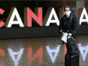 A masked passenger from the United States walks through the international arrivals area of the Calgary International Airport on Wednesday, March 18, 2020. The COVID-19 virus will soon result in the closure of non essential travel between Canada and the U.S.