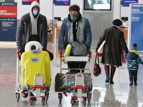Masked travellers move through the international wing of the Calgary International Airport on Wednesday, March 18, 2020.