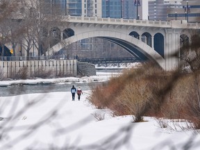 Two pedestrians take a walk by the Bow River's frozen shore on Sunday, April 5, 2020. Azin Ghaffari/Postmedia