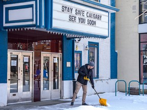 Logan Cameron, operator at Plaza Theatre in Kensington, shovels the snow in front of the closed theatre during the global pandemic on Monday, April 6, 2020.