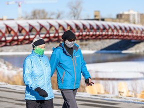 Two pedestrians take a walk on Bow River Pathway wearing face masks on Thursday, April 16, 2020. Azin Ghaffari/Postmedia