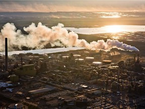 The setting sun reflects off a tailings pond behind Syncrude's oilsands upgrading facility north of Fort McMurray on June 18, 2013.