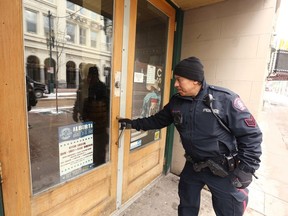 Calgary Police Sgt. Artiga checks a door of a business on Stephen Avenue to make sure it's secure on Thursday, April 2, 2020 as part of their regular downtown patrol. Police in Calgary were on the watch for criminals breaking into shops that were closed due to the coronavirus outbreak.