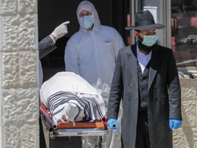 An Israeli rabbi walks next to the body former Sephardic chief rabbi of Israel Eliahu Bakshi-Doron, who died from complications of the coronavirus infection the previous last night, during his funeral at the har HaMenuchot cemetery in Jerusalem on April 13, 2020.